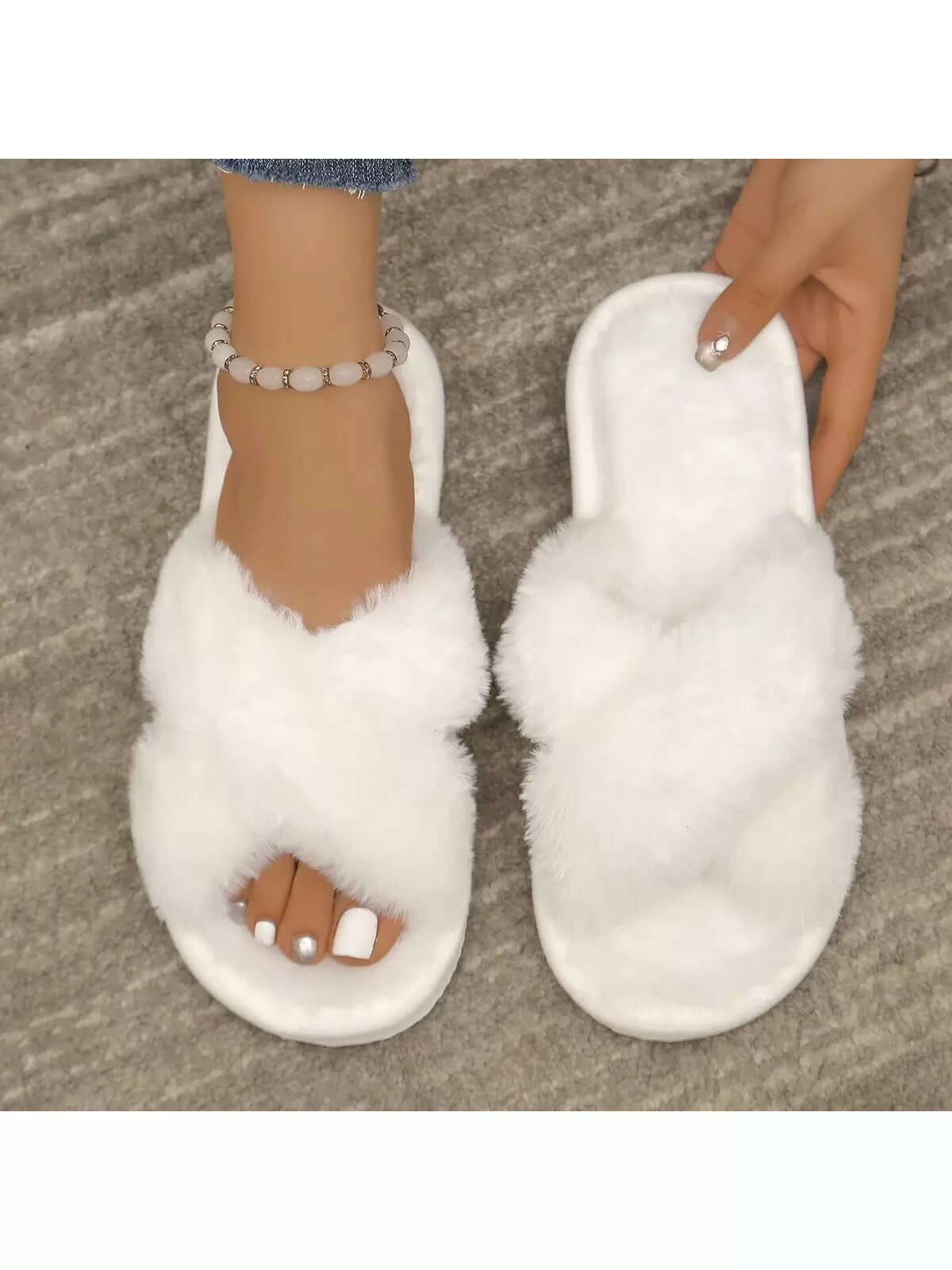 Close-up of white Axon Cloud-Soft cross strap fur slippers worn with denim jeans and a stylish anklet.